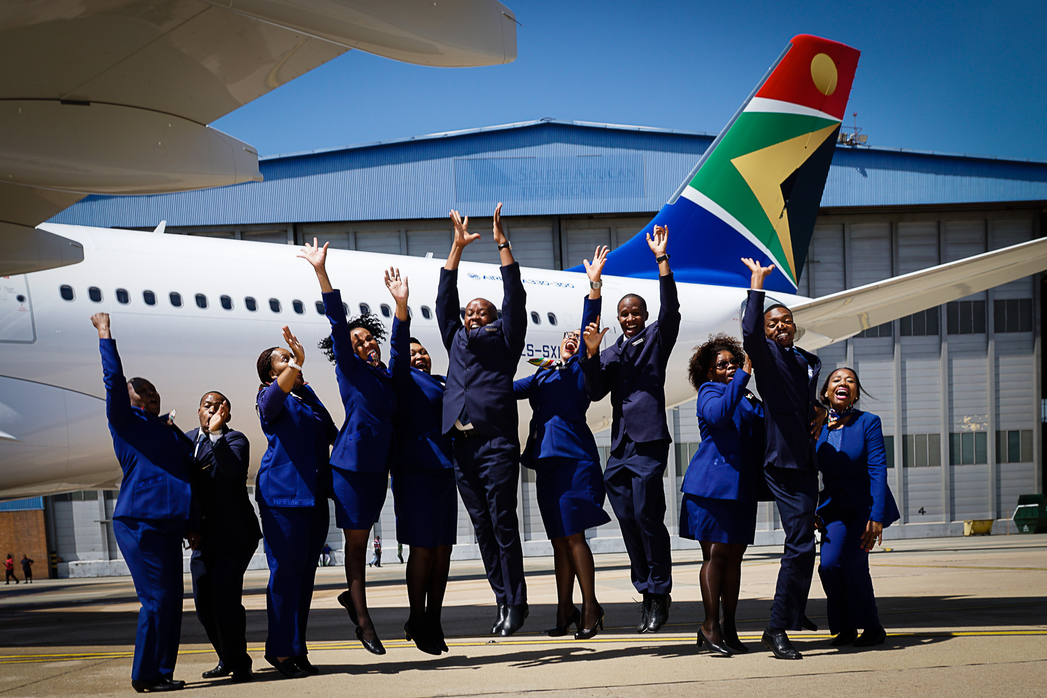 a group of people in blue uniforms standing in front of an airplane