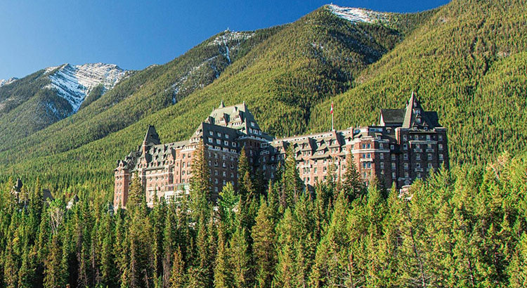 a large building surrounded by trees with Banff Springs Hotel in the background
